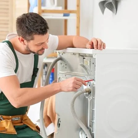 Technician checking the rear hose connections of a washing machine