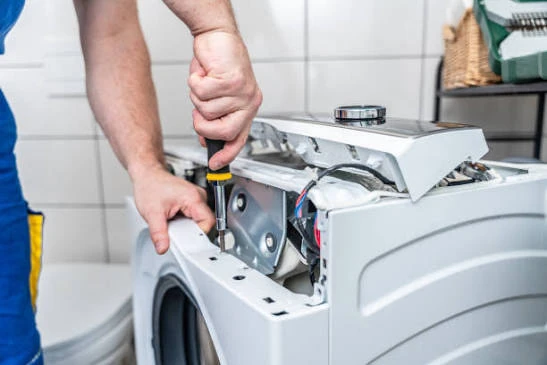 Close-up of a technician repairing the upper mechanism of a washing machine
